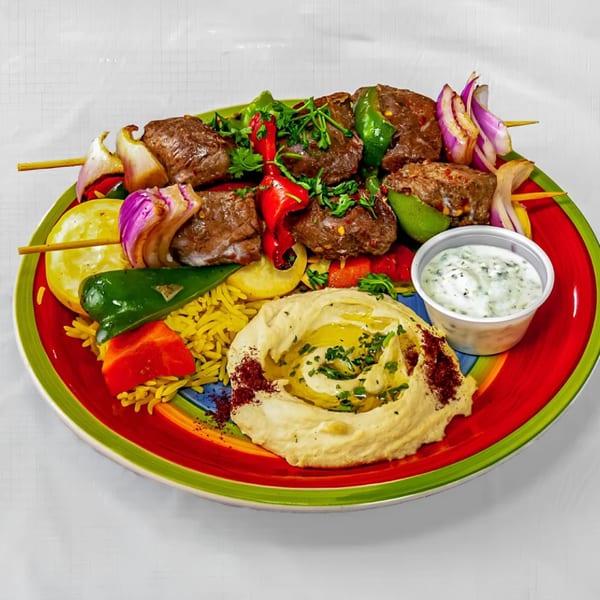 KINZI's Mediterranean beef kebab with vegetables, yellow rice, hummus, and a side of tzatziki sauce.